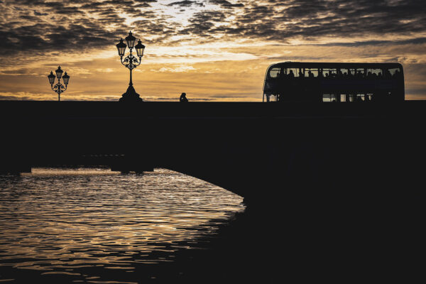 Photography silhouette technique - dramatic sunrise over Putney Bridge, man walking over the bridge during golden hour