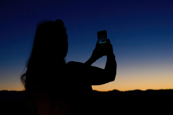 Photography silhouette technique - woman holding a mobile phone during blue hour